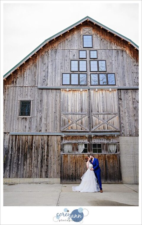 Bride and Groom kissing framed by the barn doors at Rivercrest Farm on their wedding day