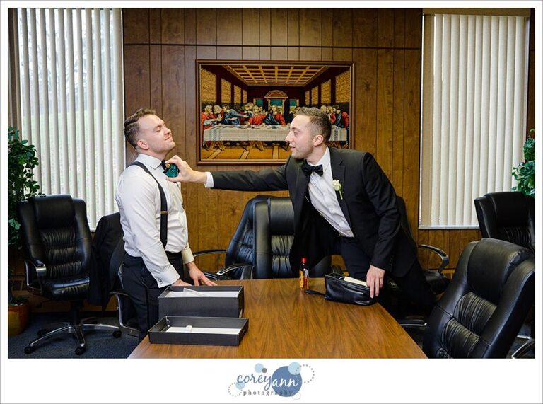Groomsman helping groom with bow tie before wedding in Canton Ohio