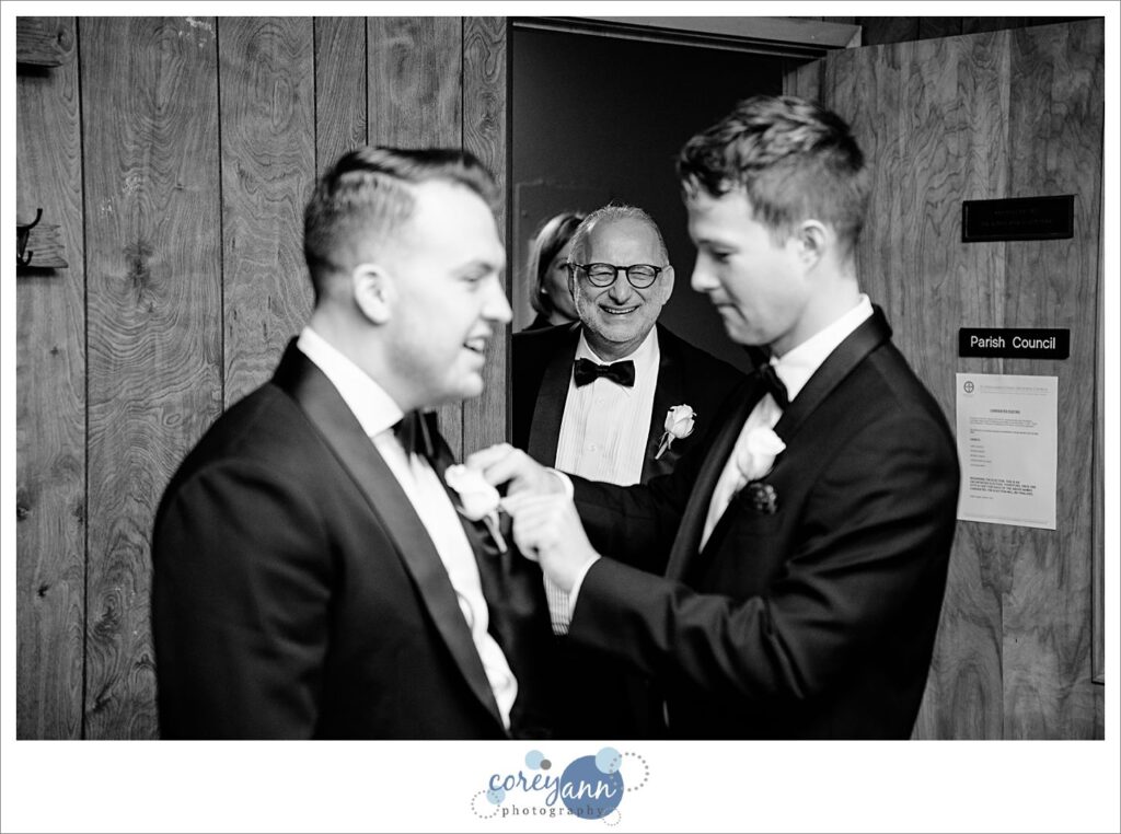 Groomsman helping groom with bow tie before wedding in Canton Ohio