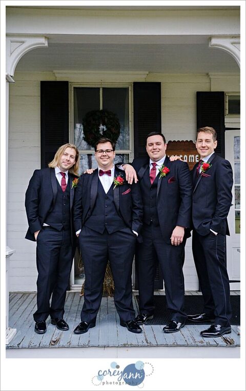 Groom and groomsman wearing black tuxes with red ties and pocketsquares
