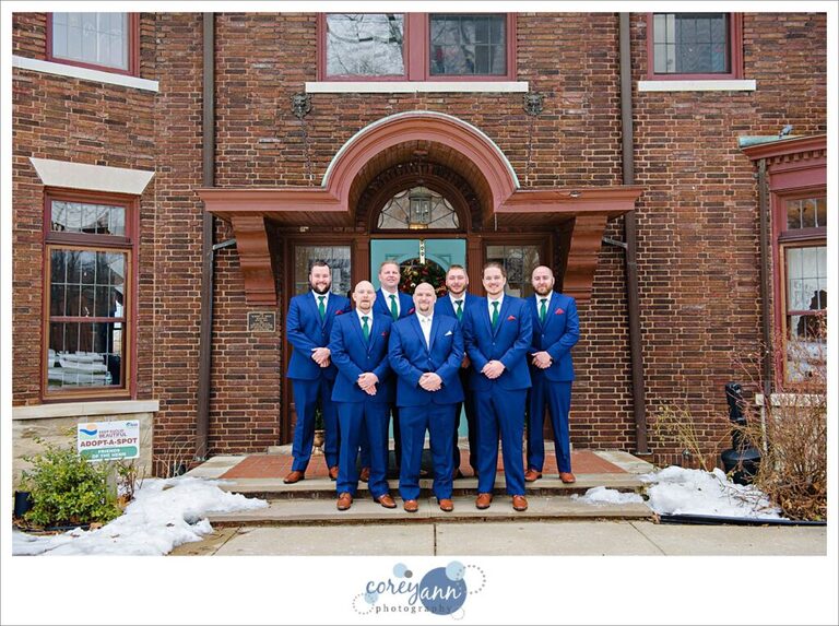 Groom and groomsman pose outside of Henn Mansion before a February wedding