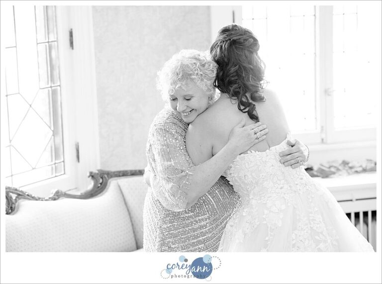 Bride and Mom hug after getting wedding dress on before wedding in Ohio
