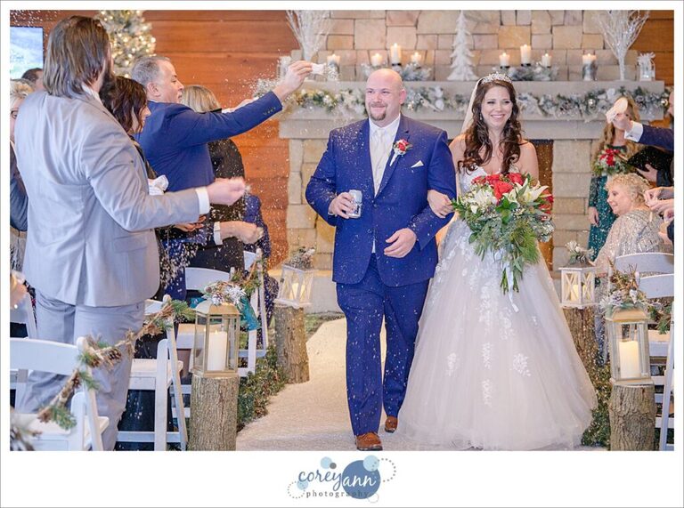 Guests tossing snow on bride and groom as they process down the aisle after wedding ceremony