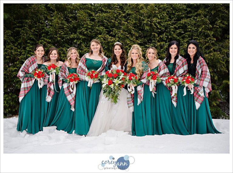 Bride and bridesmaids who are wearing green and all holding christmas themed floral bouquets