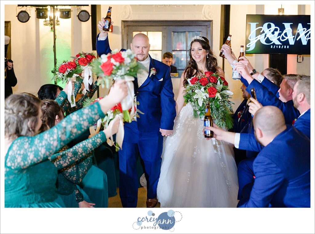 Bride and groom entering to bridal party raising their beers