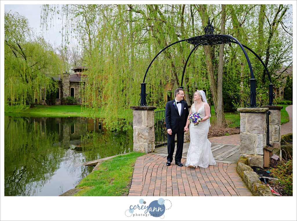 Bride and Groom walking on path by bridge at Gervasi Vineyard after wedding