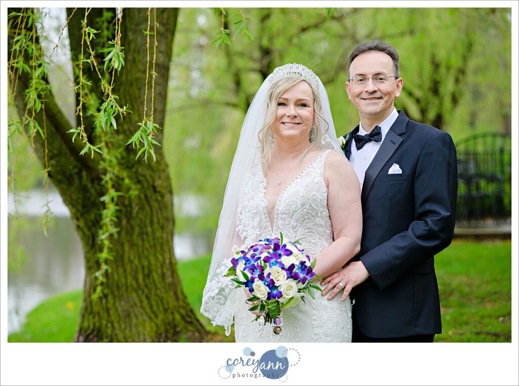 Bride and groom posing beneath a willow tree after wedding ceremony at Gervasi Vineyard in the spring