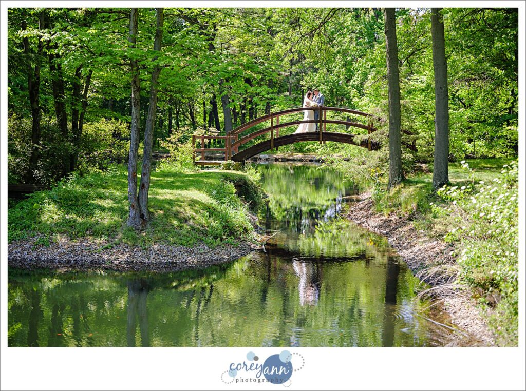 bride and groom on bridge over lagoons at stan hywet after their wedding
