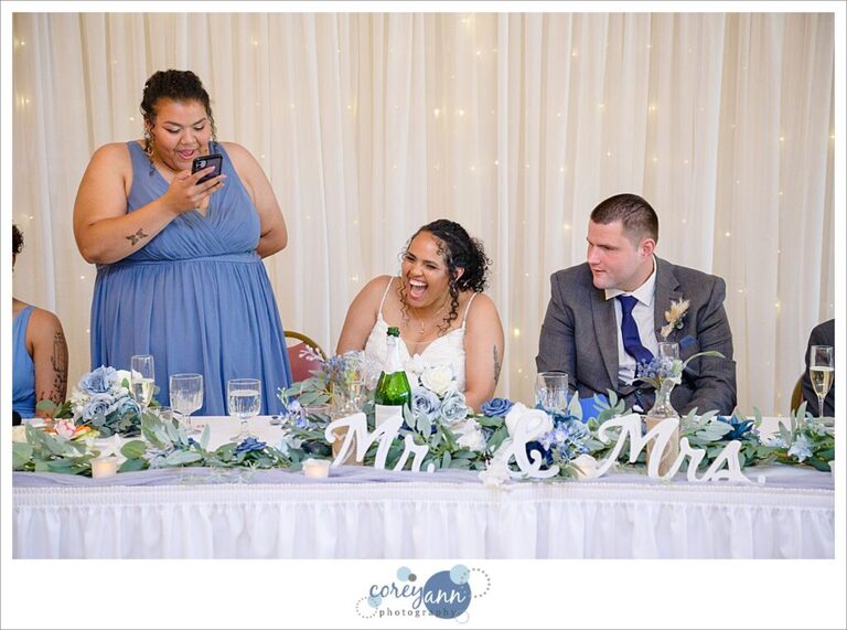 A bride and groom sitting while one of their bridal party gives a toast during the wedding reception in Akron Ohio