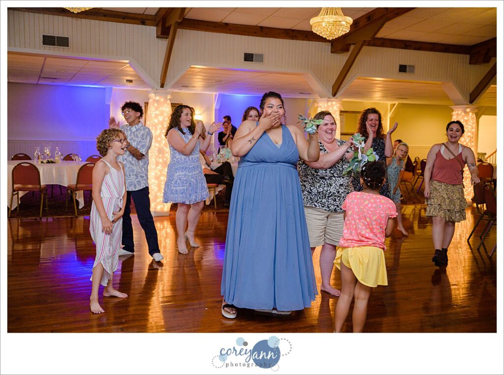 A bridesmaid wearing a blue azazie dress catches the bouquet during a wedding reception in Akron Ohio