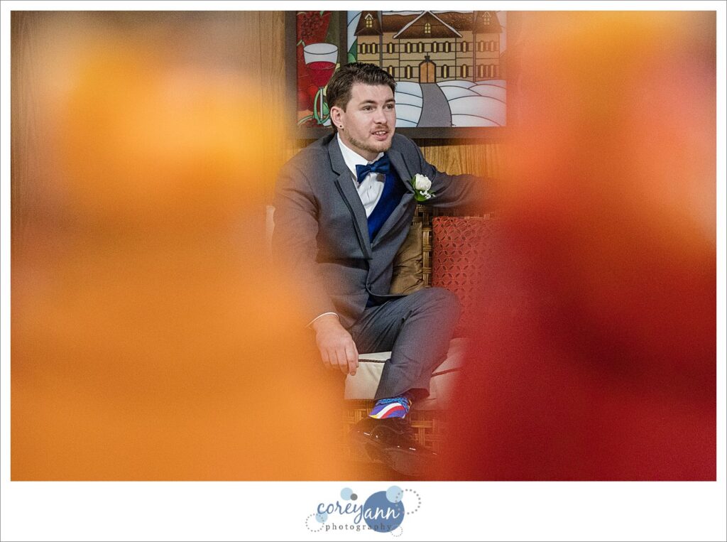 Groom sitting in a charcoal tux with a blue bow tie at Amy's Rustic Event Center in Valley City, Ohio