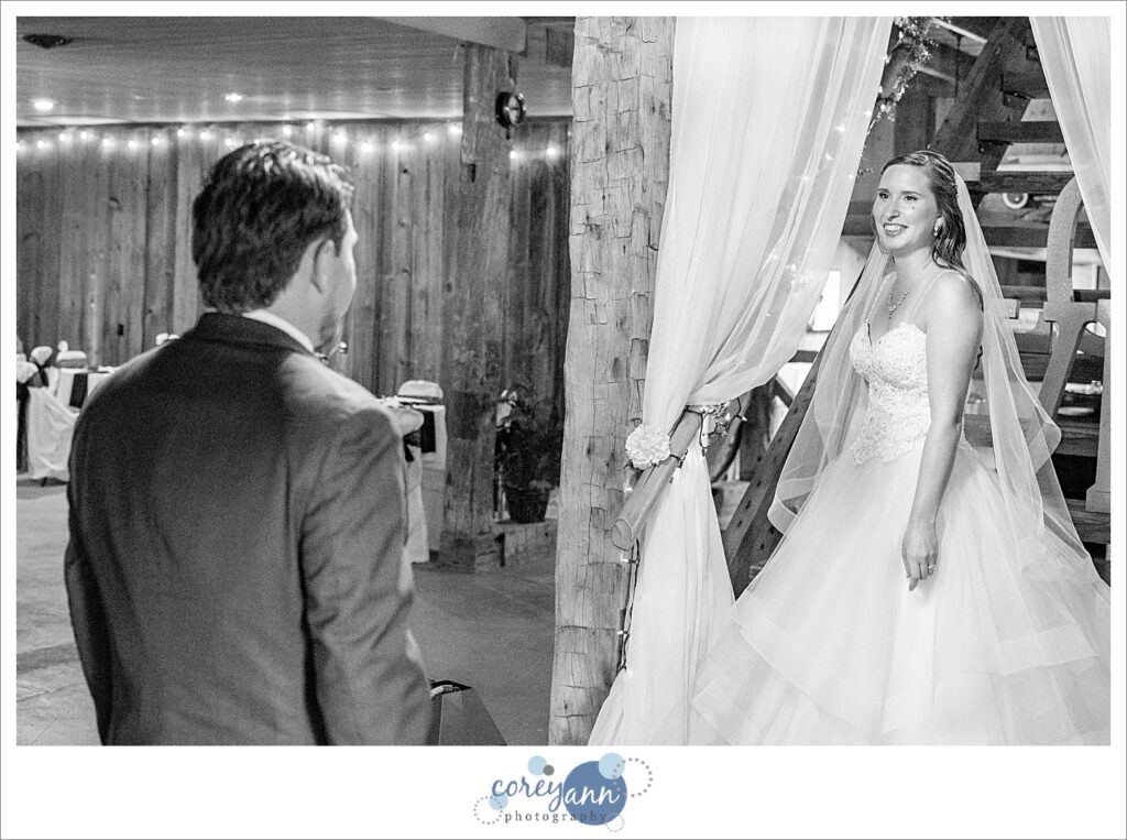 Black and white photo of a bride and groom first look where both are smiling at each other at Amy's Rustic Event Center in Valley City, Ohio