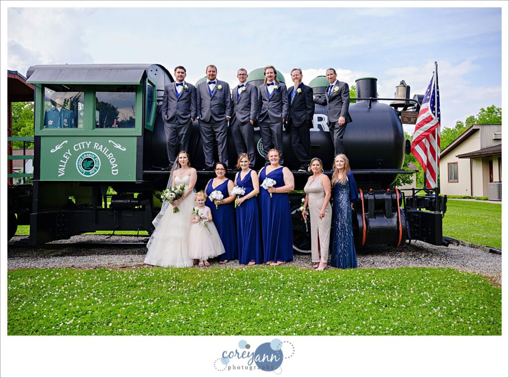 Bride and groom with their wedding party and family posing on a train engine at Liverpool Township Museum in Ohio