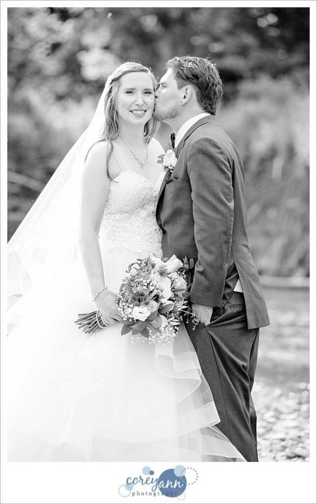 Black and white portrait of a groom kissing the cheek of a bride in valley city, ohio