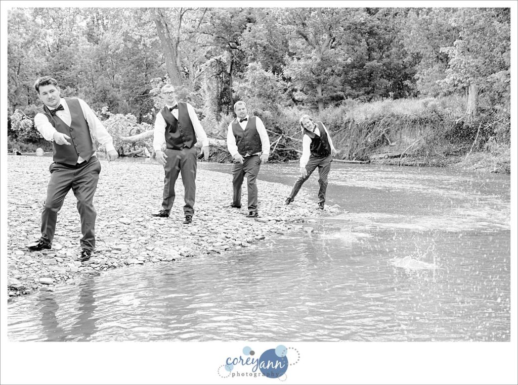 Groom and groomsman skipping rocks on a river in Valley City Ohio