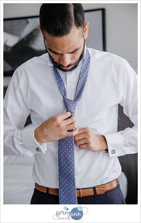 Groom getting ready by tying a tie for wedding in Cleveland at The Arcade