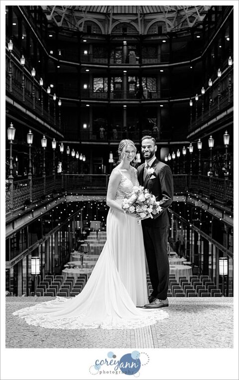 Black and white photo of a bride and groom standing inside the Hyatt Regency Cleveland at The Arcade before their wedding