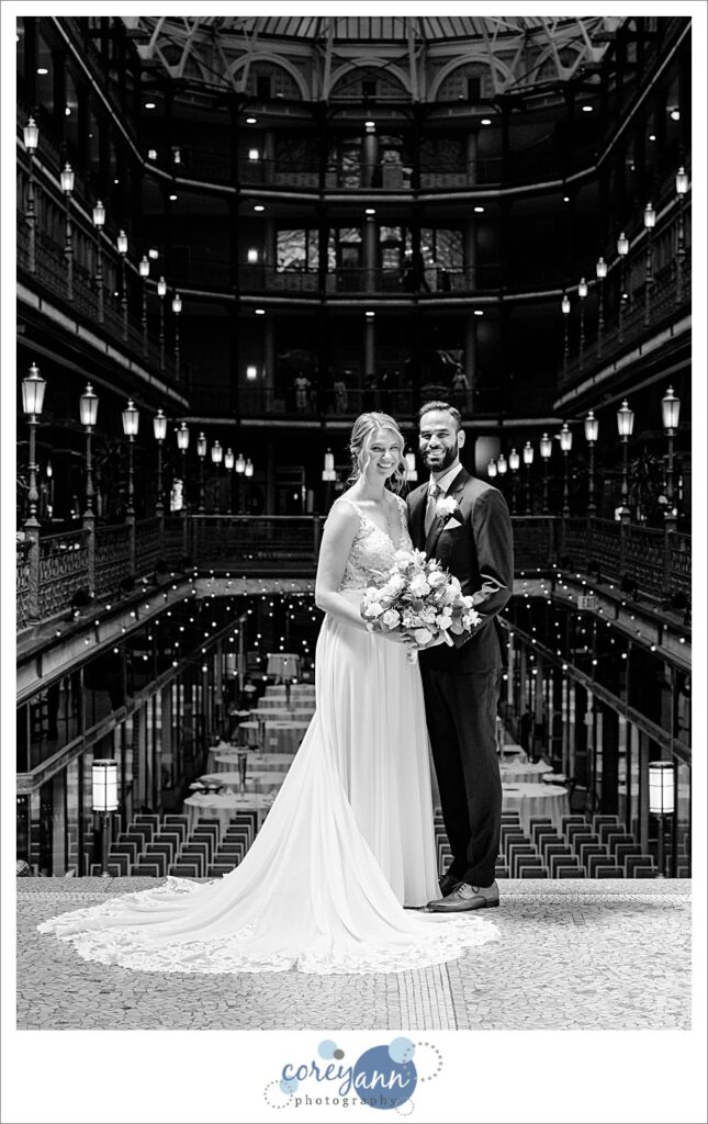 Black and white photo of a bride and groom standing inside the Hyatt Regency Cleveland at The Arcade before their wedding