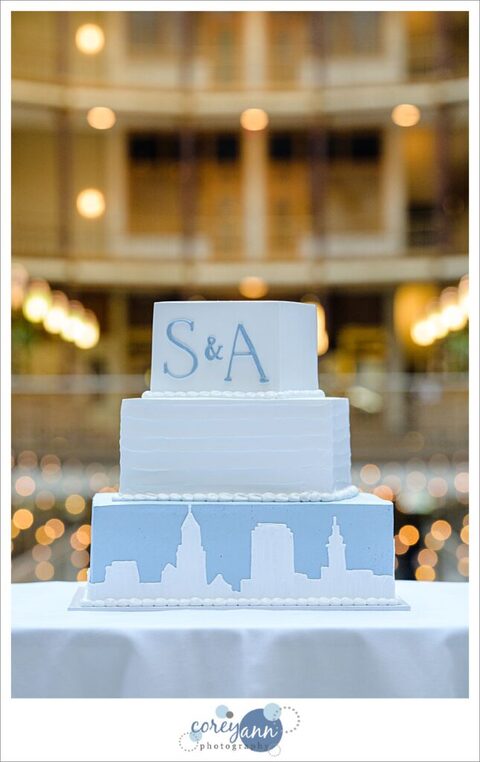 Blue and white wedding cake with skyline at Hyatt Regency Cleveland at The Arcade by Wild Flour Bakery