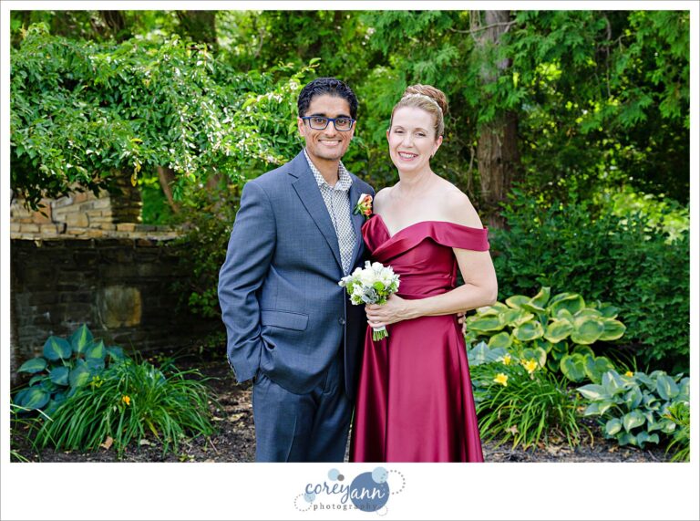 bride wearing a wed wedding dress posing next to her groom in a grey suit outside in the garden for an intimate outdoor wedding ceremony in gates mills, ohio at hawken upper school