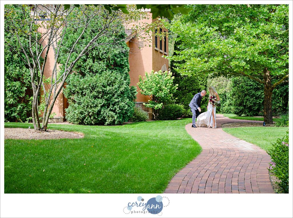 Bride's father floofing her train before walking down the aisle at gervasi vineyard in canton ohio