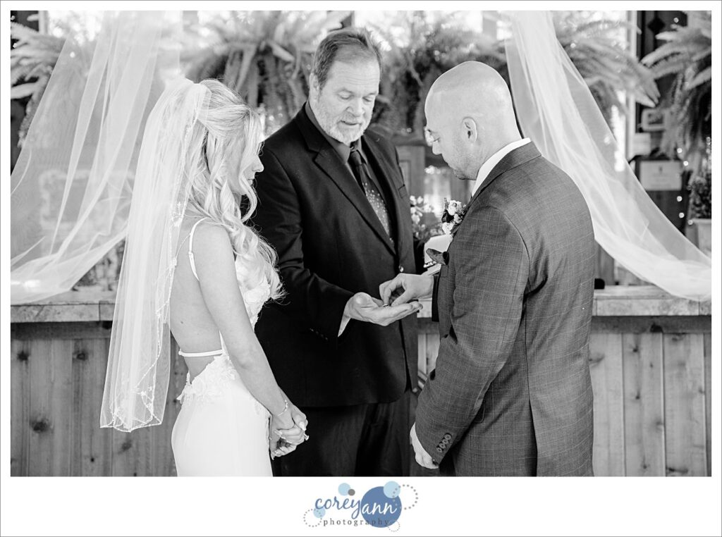 Bride and groom exchanging rings during a wedding ceremony at Gervasi Vineyard in the Conservatory in Canton Ohio