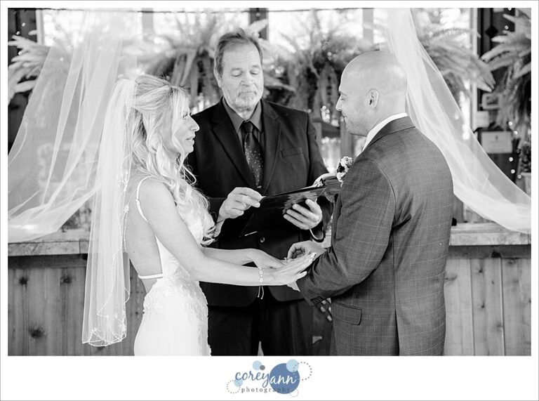 Bride and groom exchanging rings during a wedding ceremony at Gervasi Vineyard in the Conservatory in Canton Ohio