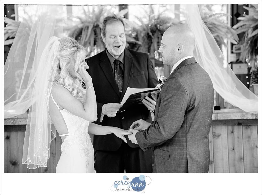 Bride and groom exchanging rings during a wedding ceremony at Gervasi Vineyard in the Conservatory in Canton Ohio
