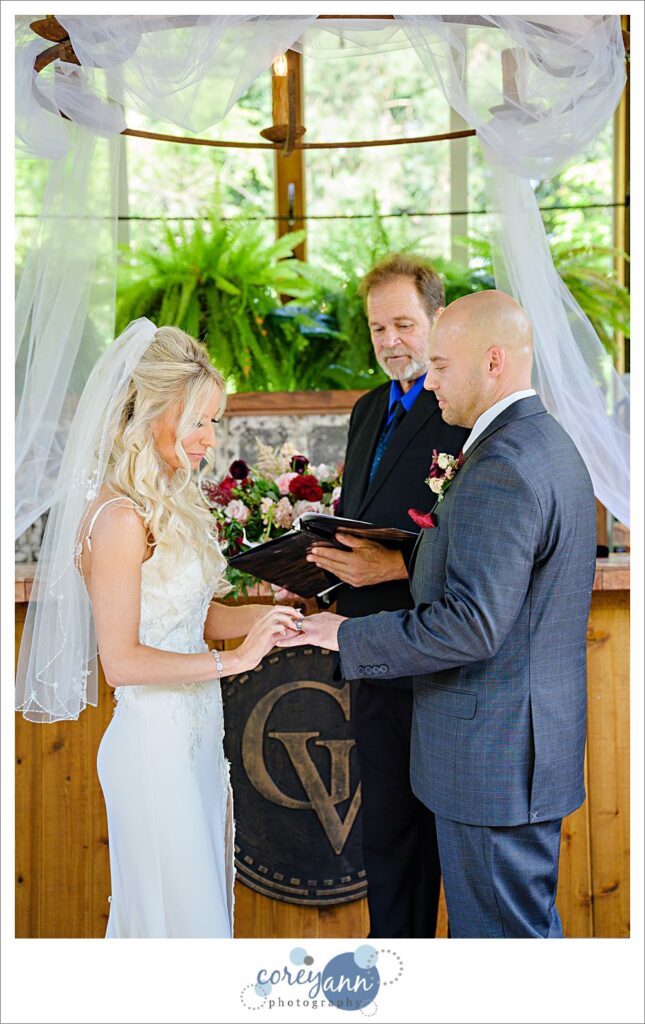 Bride and groom exchanging rings during a wedding ceremony at Gervasi Vineyard in the Conservatory in Canton Ohio