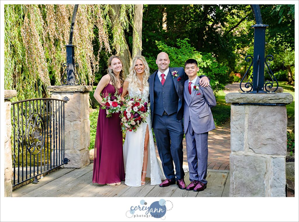 Bride and Groom with their kids standing on the bridge over the pond at Gervasi Vineyard