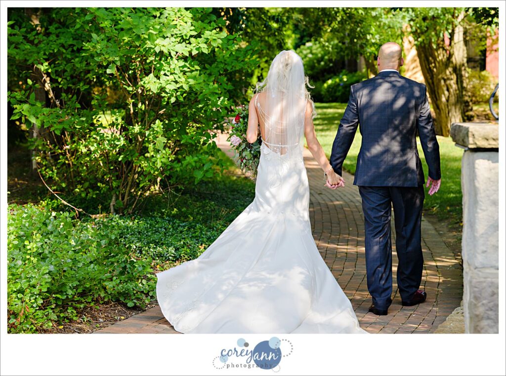 Bride and groom walking away on a path at Gervasi Vineyard