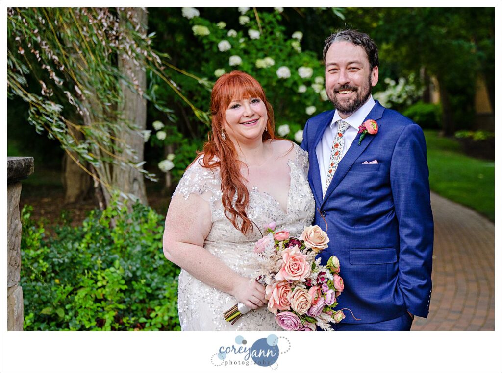Bride and groom smiling and posing on the bridge during the summer at Gervasi Vineyard after their wedding ceremony