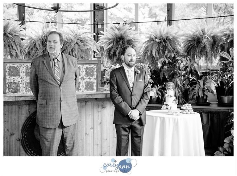 Groom waiting for bride to come down the aisle in black and white