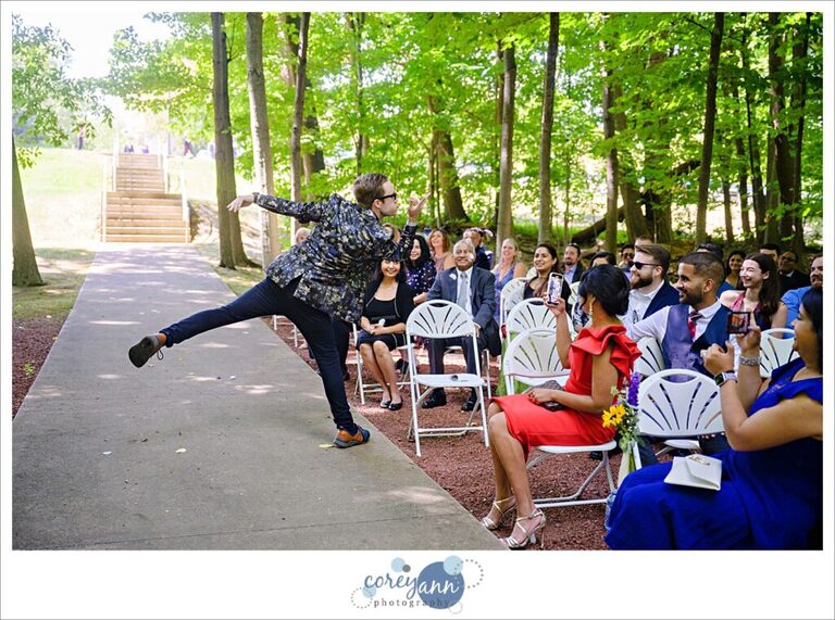 Flower Dude blowing rose petals at guests sitting for a wedding ceremony at Manakiki Golf Course in Willoughby Ohio