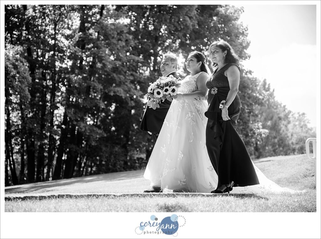 Bride and her parents walking along the sidewalk to the outdoor ceremony spot at Manakiki Golf Course
