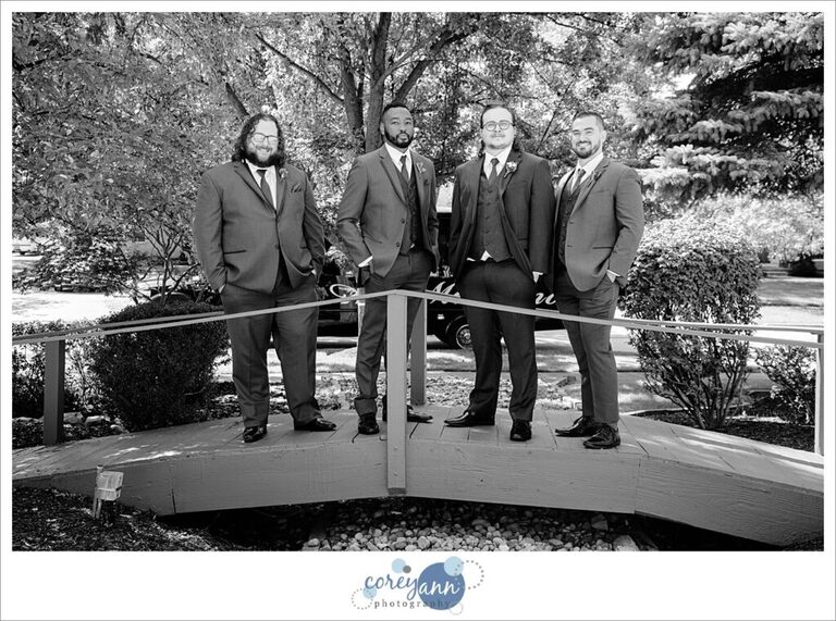 Groom and Groomsman posing on a small bridge 