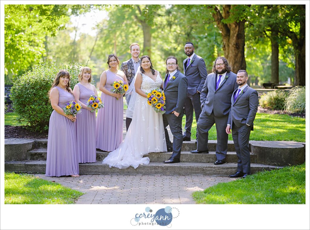 Bridal Party with bridesmaids in lavender dresses holding sunflower bouquets and groomsman in grey suits