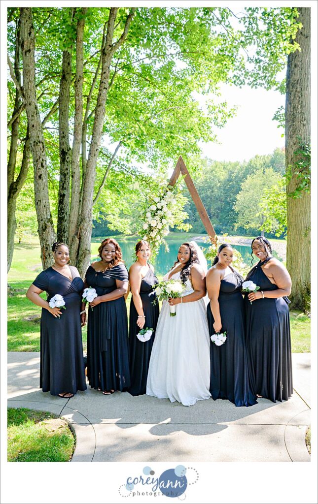 Bride and her bridesmaids posing in front of arch at Sun Valley Ohio
