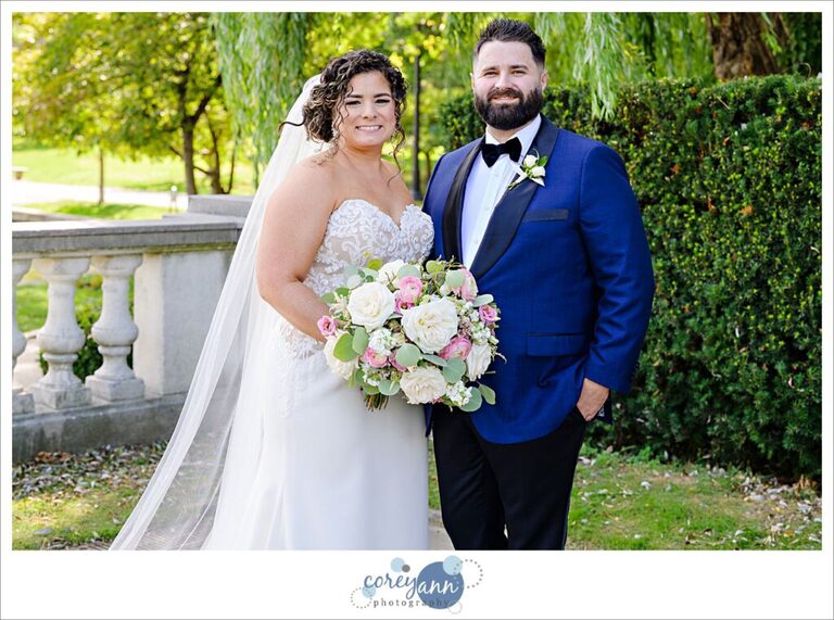 Bride and groom standing in front of greenery outside of Cleveland Museum of Art in the Summer before their wedding