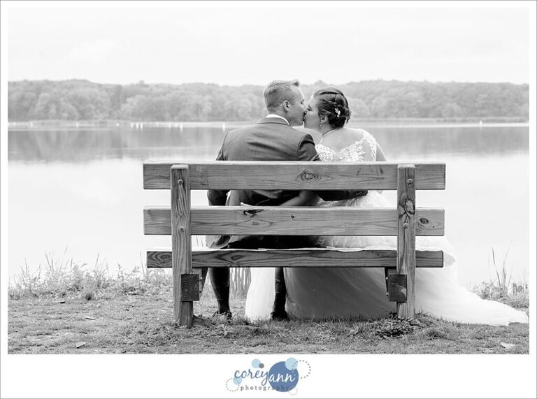 bride and groom kissing on a bench near nimisila reservoir