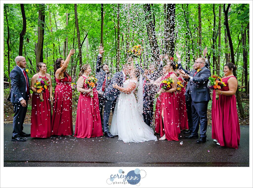 Wedding party shooting off petals around bride and groom