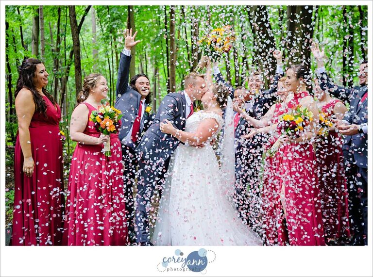 Wedding party shooting off petals around bride and groom
