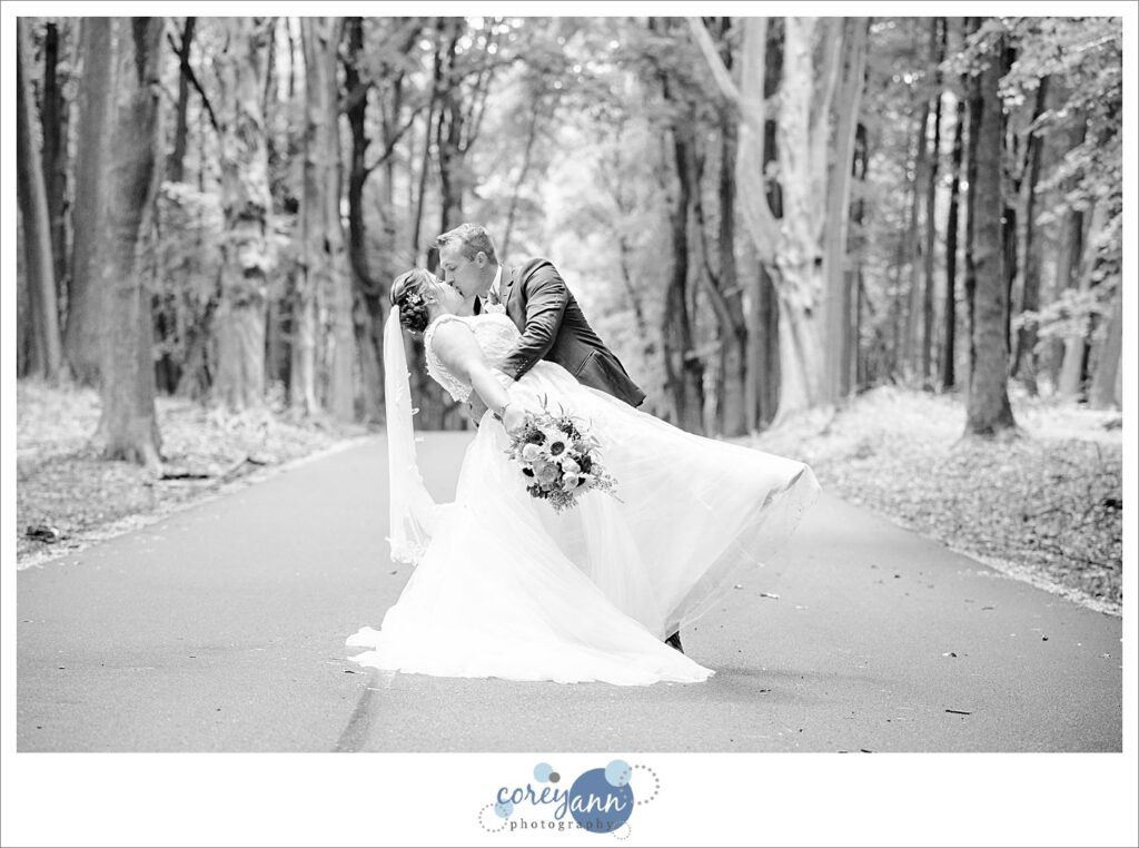 bride and groom doing a dip on a forest road in akron ohio