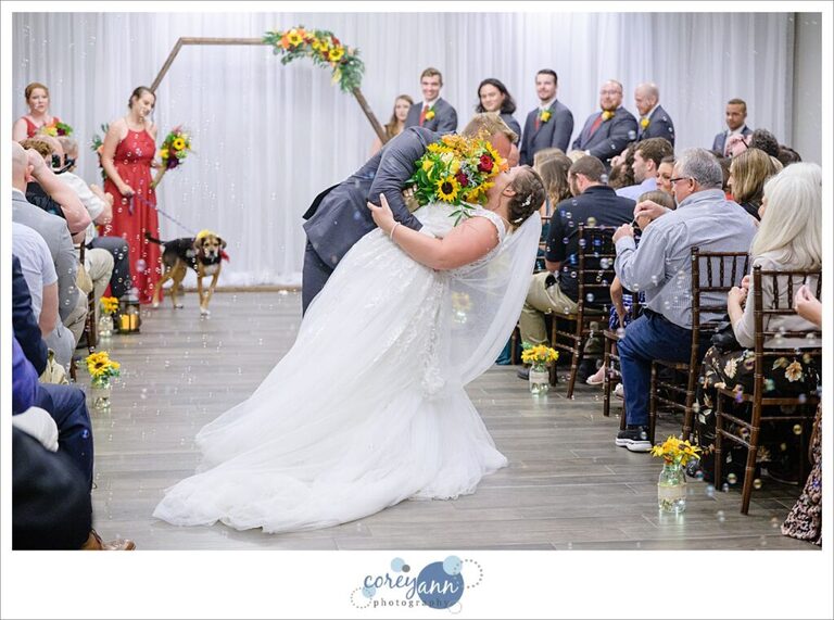 Groom dipping bride as they walk down the aisle after wedding ceremony in Akron Ohio