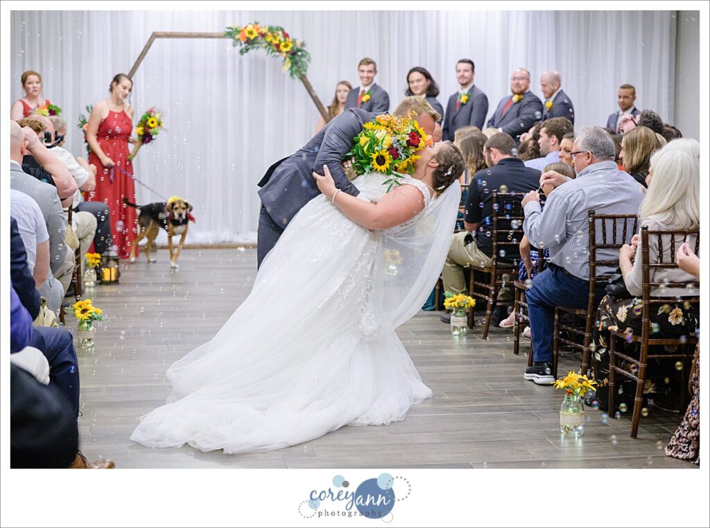 Groom dipping bride as they walk down the aisle after wedding ceremony in Akron Ohio