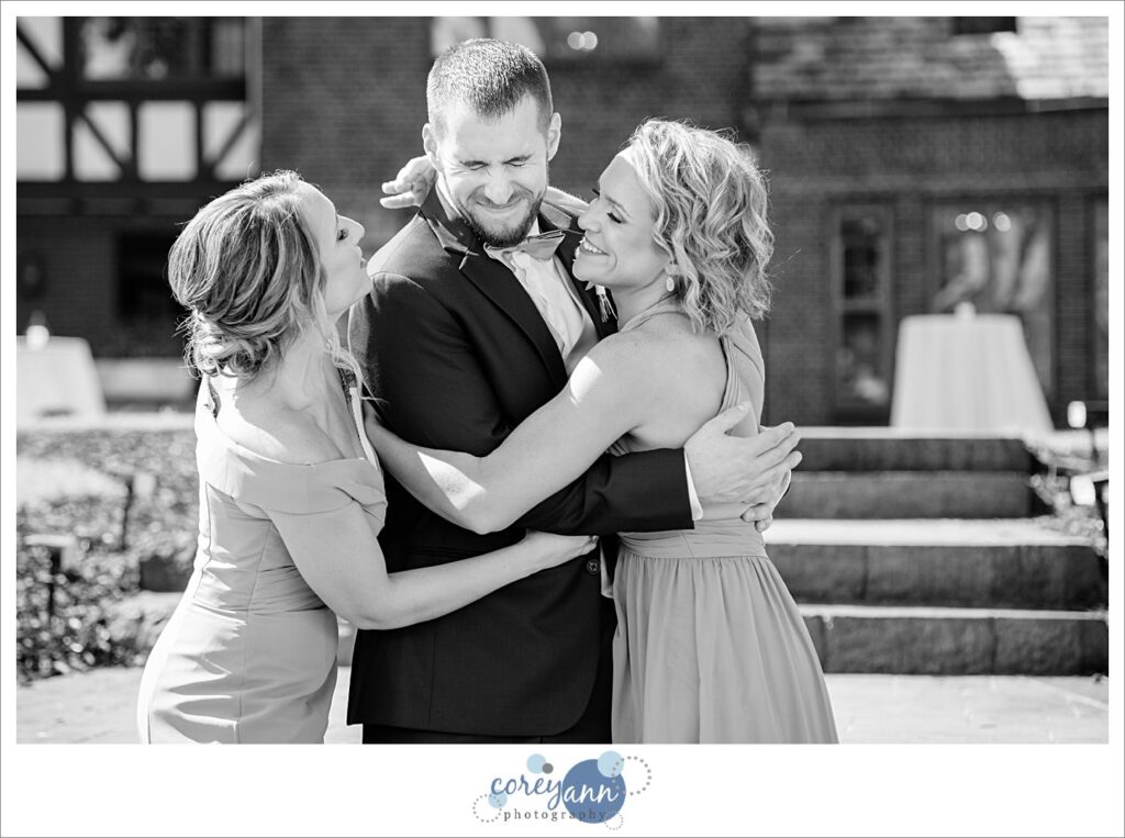 Groom doing first look with his sisters before wedding at Tudor House on Portage Lakes in Akron Ohio