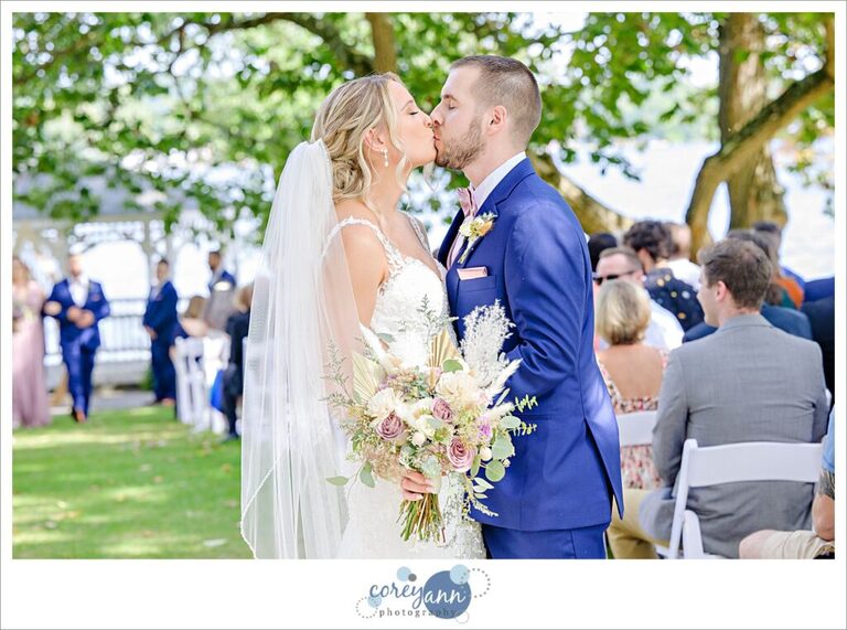 Bride and groom kissing in the aisle after outdoor wedding ceremony on Portage Lakes