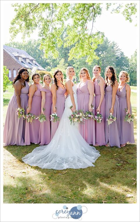 Bride alongside bridesmaids in Azazie dresses in pink and purple