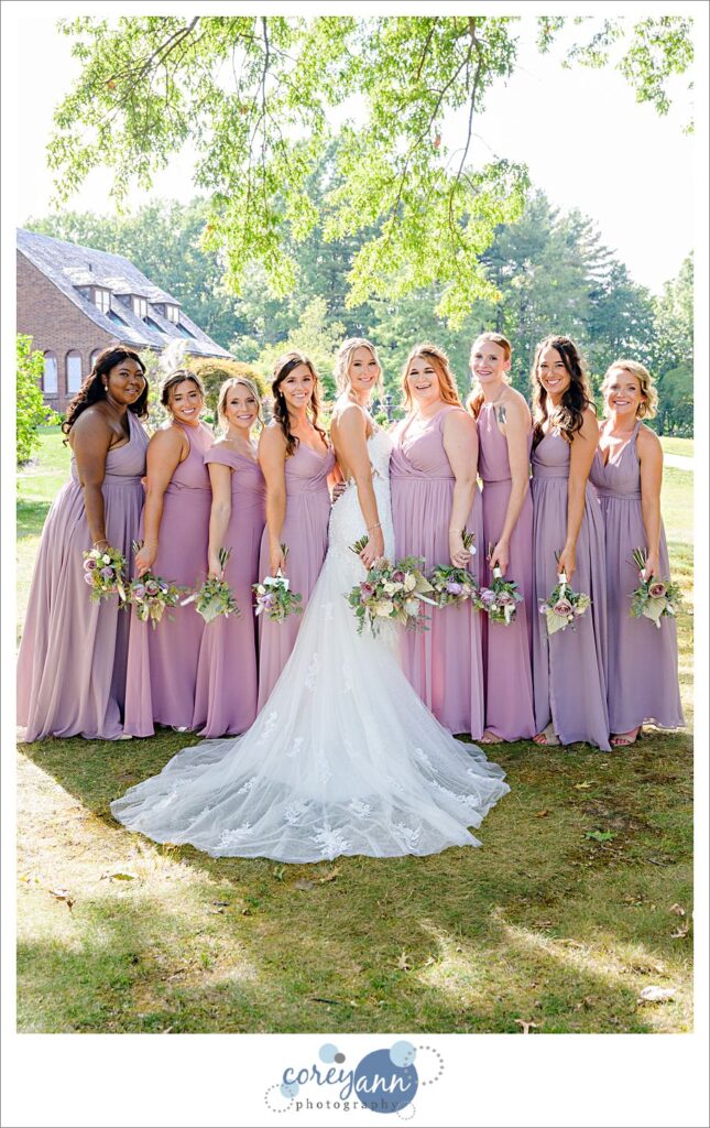 Bride alongside bridesmaids in Azazie dresses in pink and purple