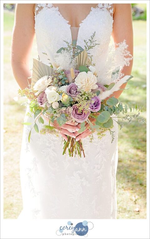 Bride holding whimsical bridal bouquet with lavender roses and greenery